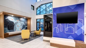 A modern lobby with a large map mural, seating area, and a TV screen.