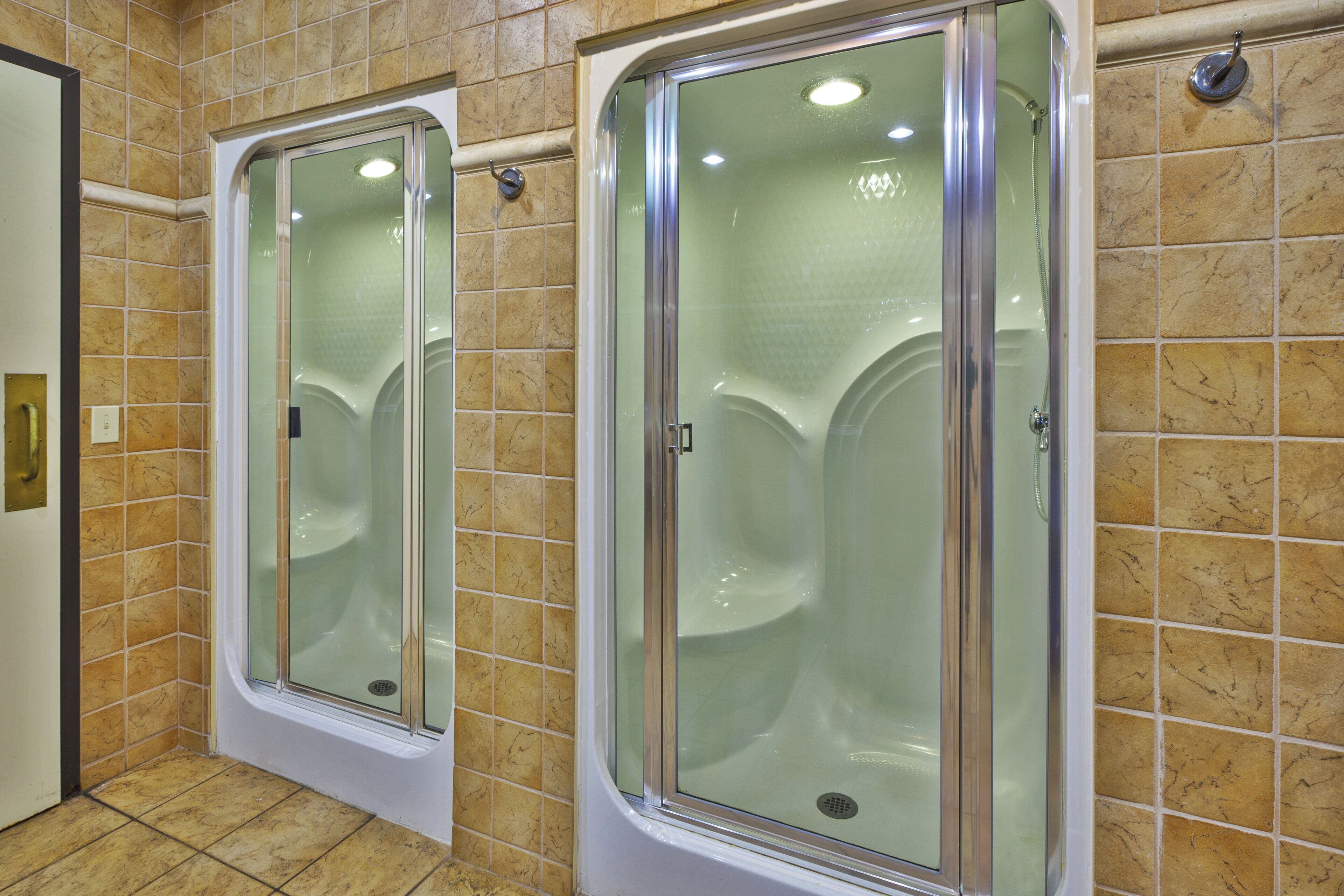 A bathroom with two glass-enclosed shower stalls and a tiled floor.