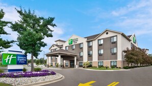 A Holiday Inn Express & Suites building with a modern design, featuring a large entrance and a parking area with directional arrows.