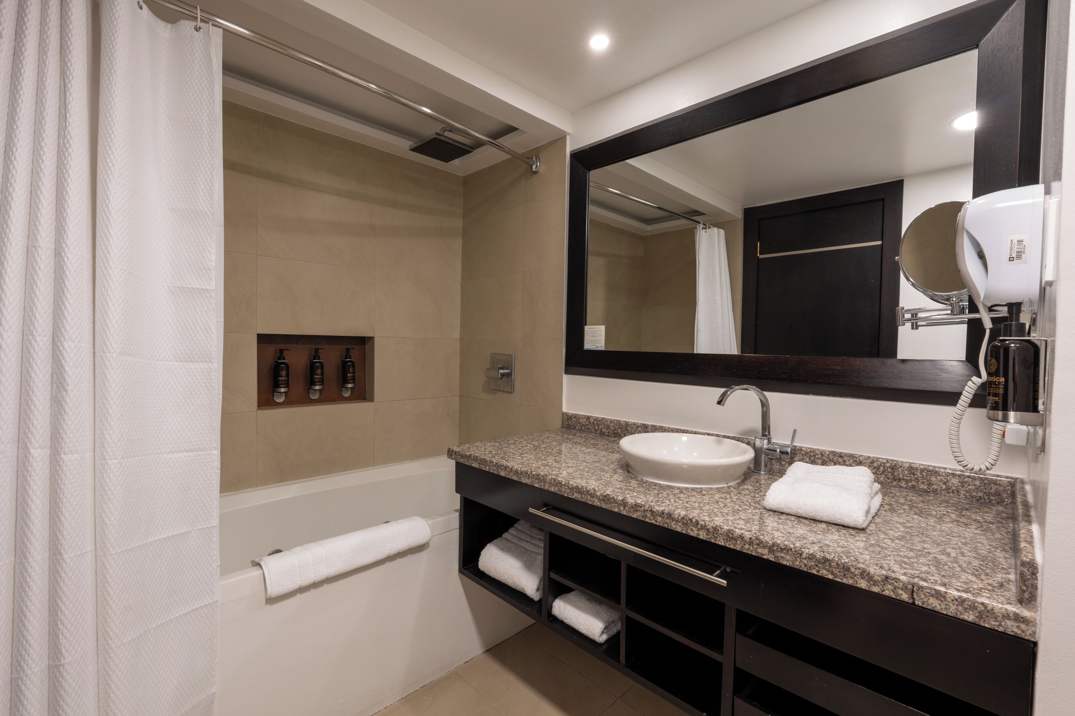 A modern bathroom with a large mirror, a sink, and a shower area.