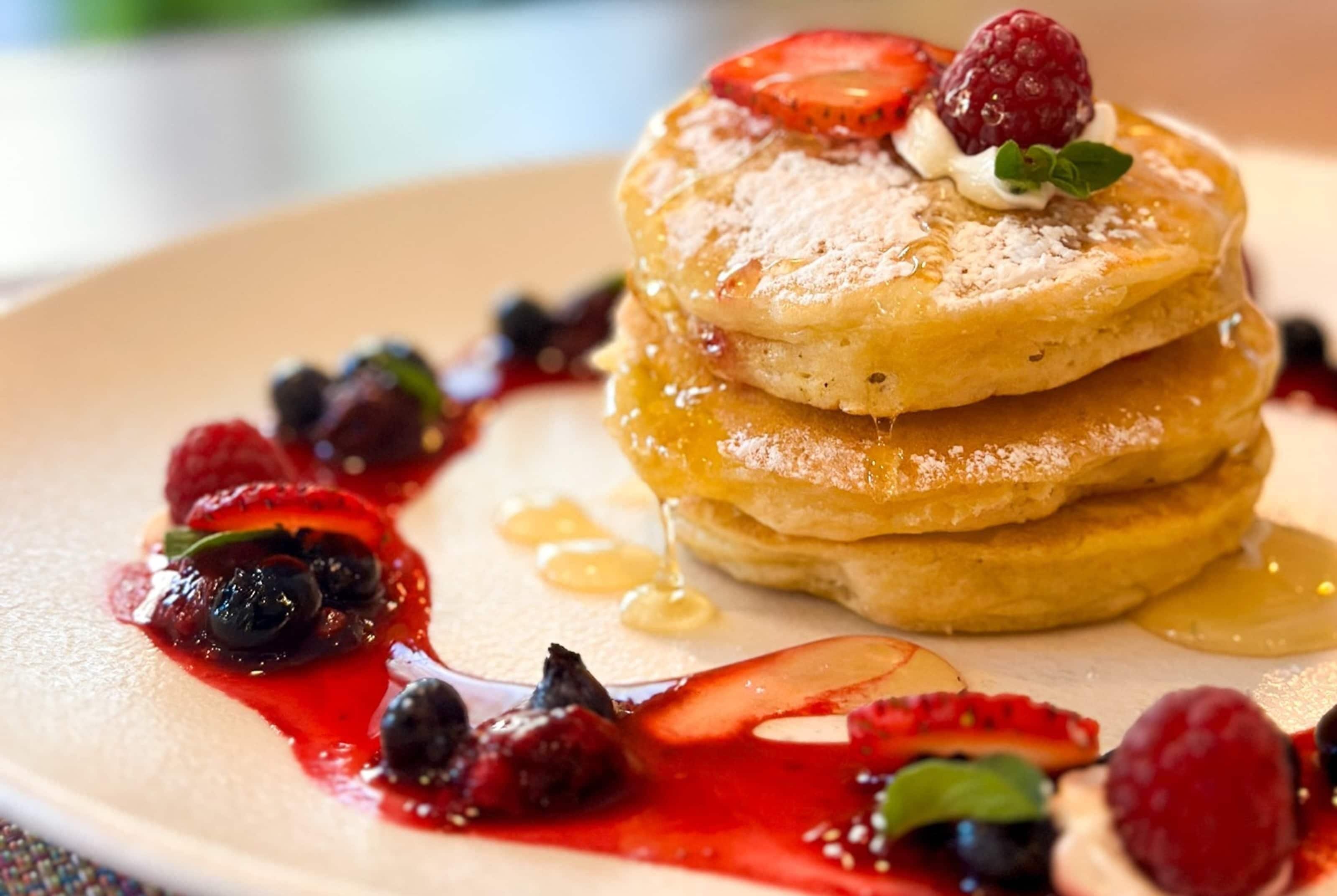Ein Stapel Pfannkuchen mit Beeren und Ahornsirup.