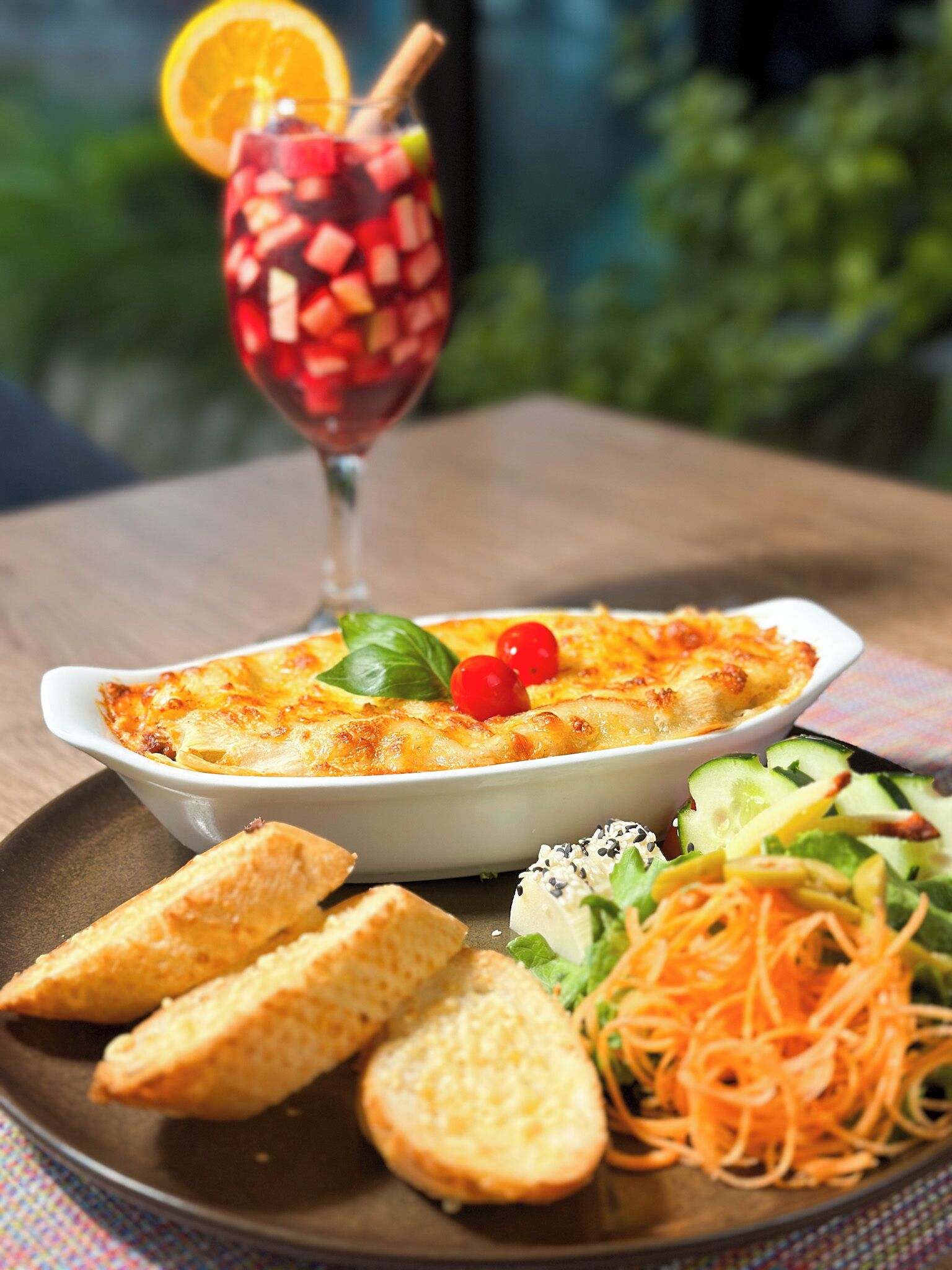 En portion bagt pasta med en salat og brød på en tallerken.