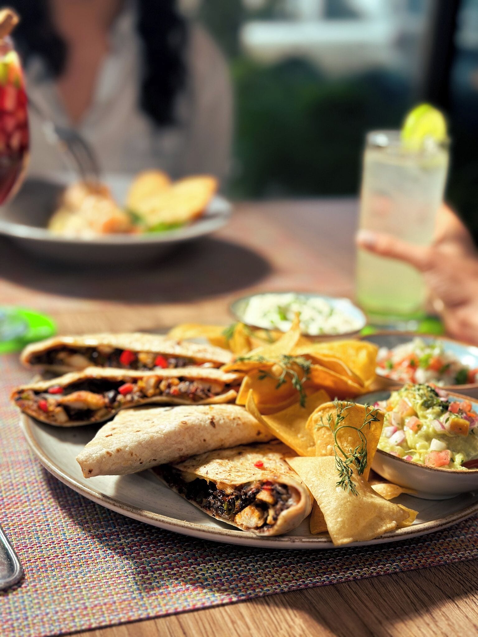 Une assiette de tacos, des chips et un bol de guacamole sur une table.
