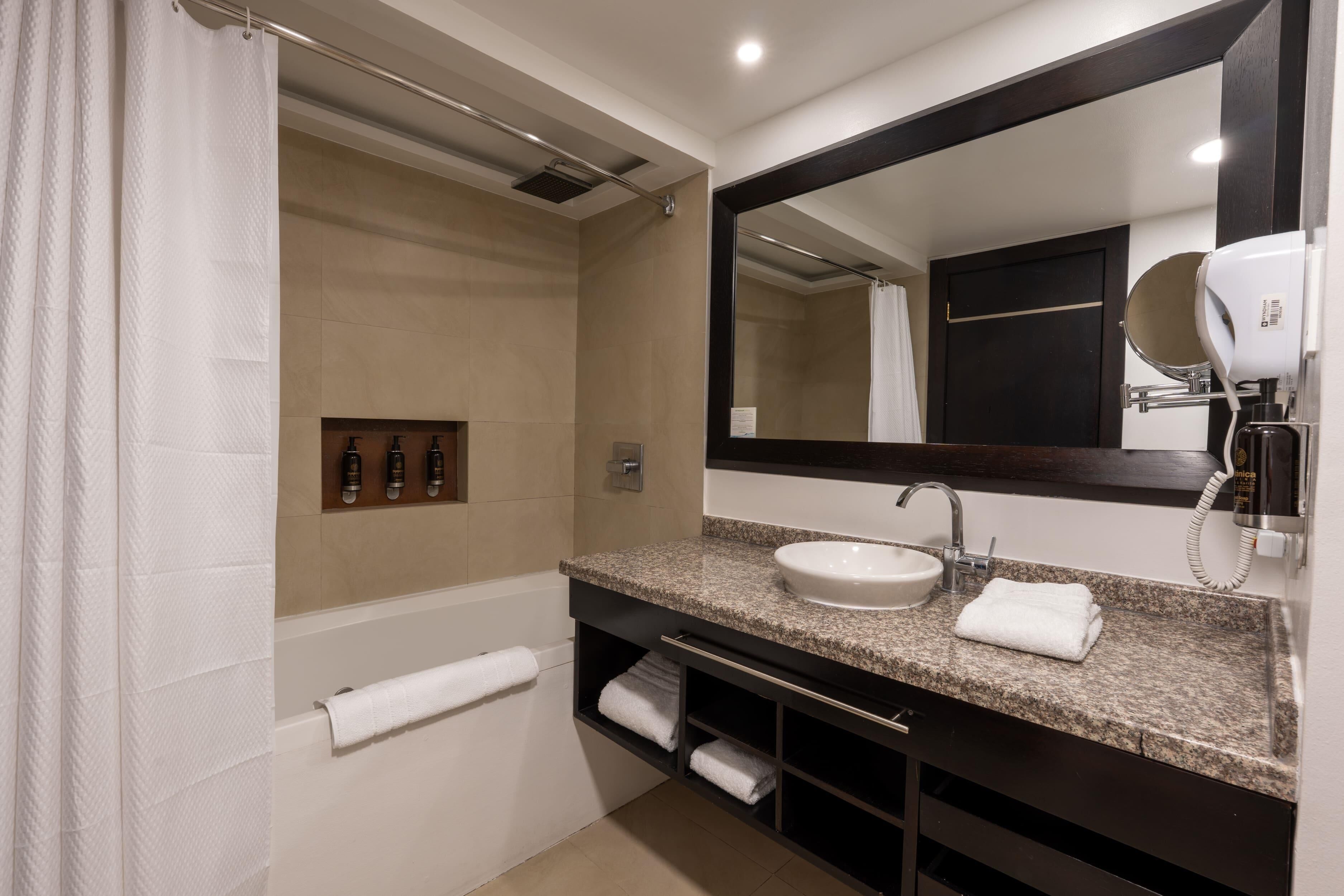 Un baño moderno con un espejo grande, un lavabo y una zona de ducha.
