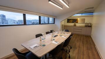 A conference room with a long table, chairs, and a city view through large windows.