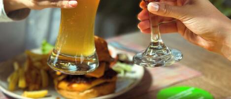 Una persona sosteniendo un vaso alto de cerveza y otro con frutas y una ramita de canela.