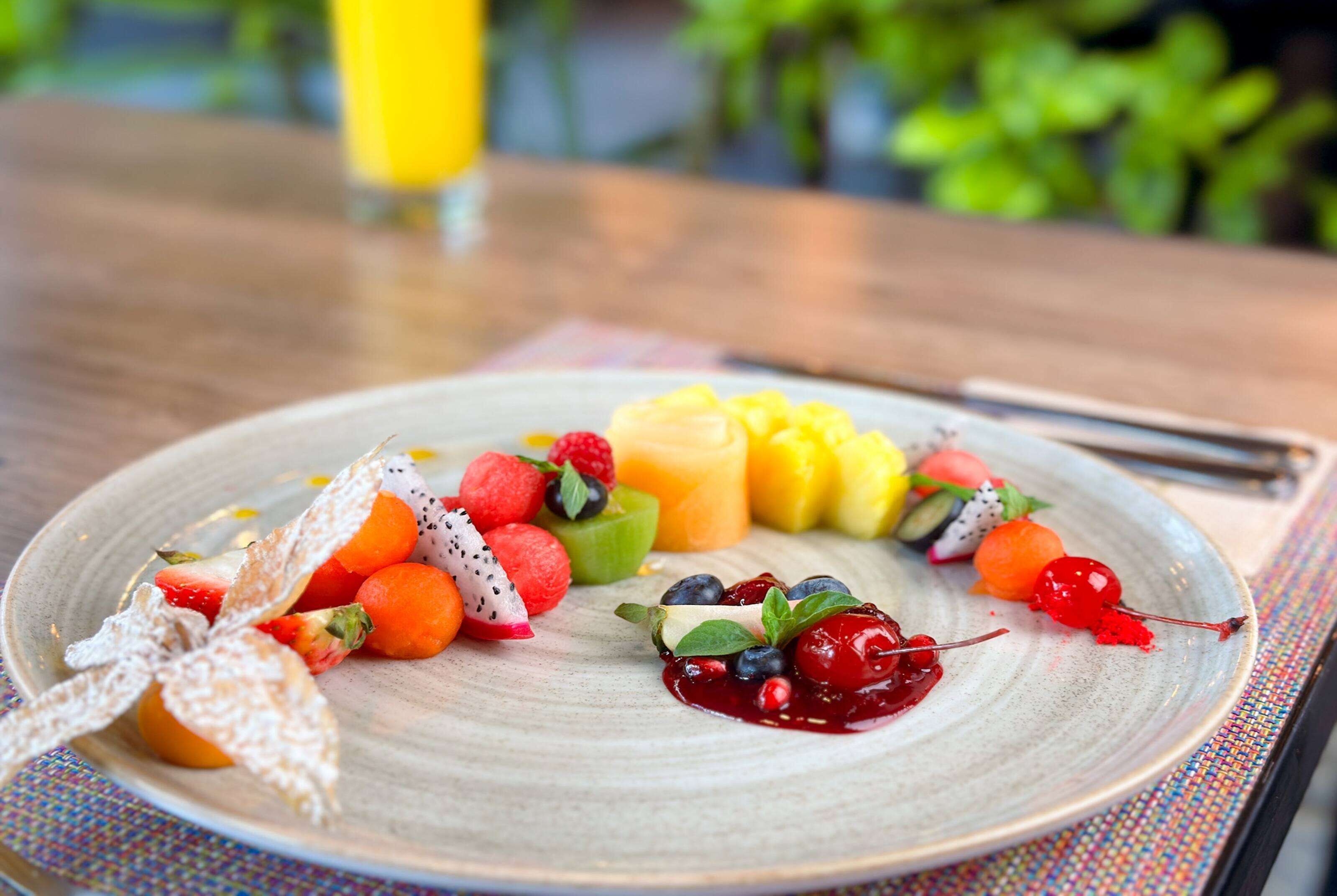 A plate of assorted fruits and a slice of cake on a table.