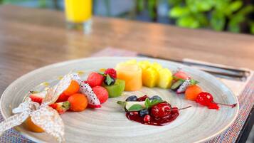 Une assiette remplie de fruits variés et une part de gâteau sur une table.