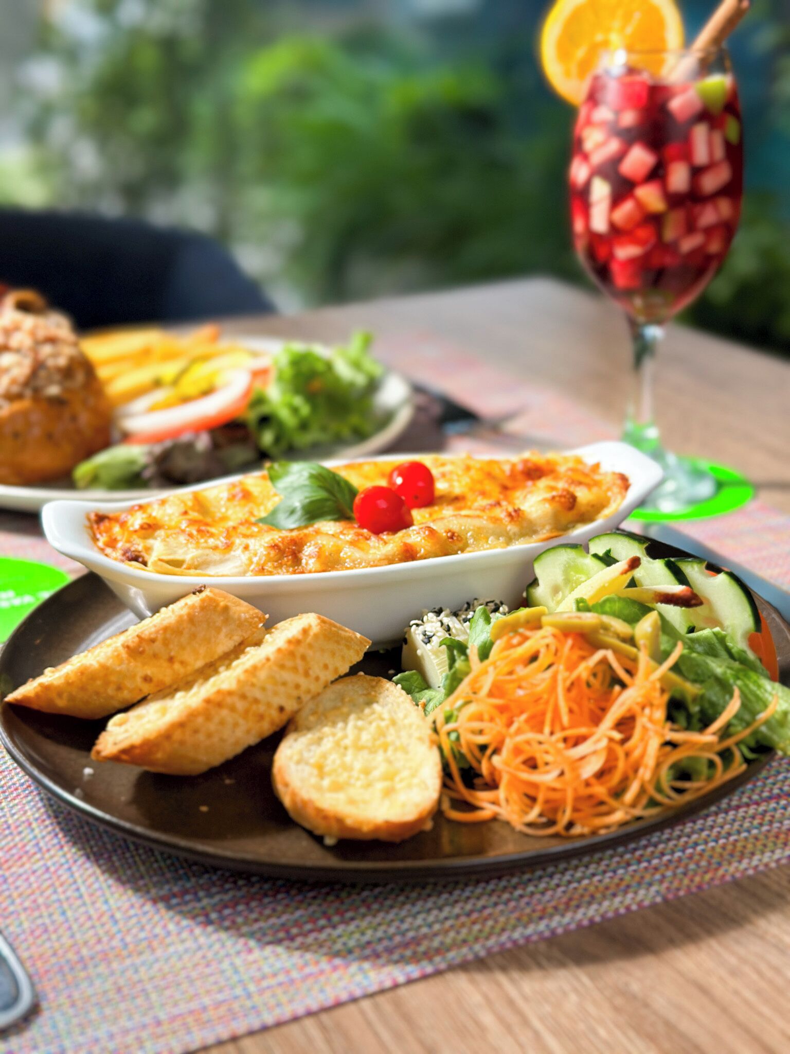 En måltid bestående av en portion pasta, en sallad och bröd, serverat på ett bord.