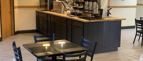 A restaurant with a bar area, tables, chairs, and a clock on the wall.