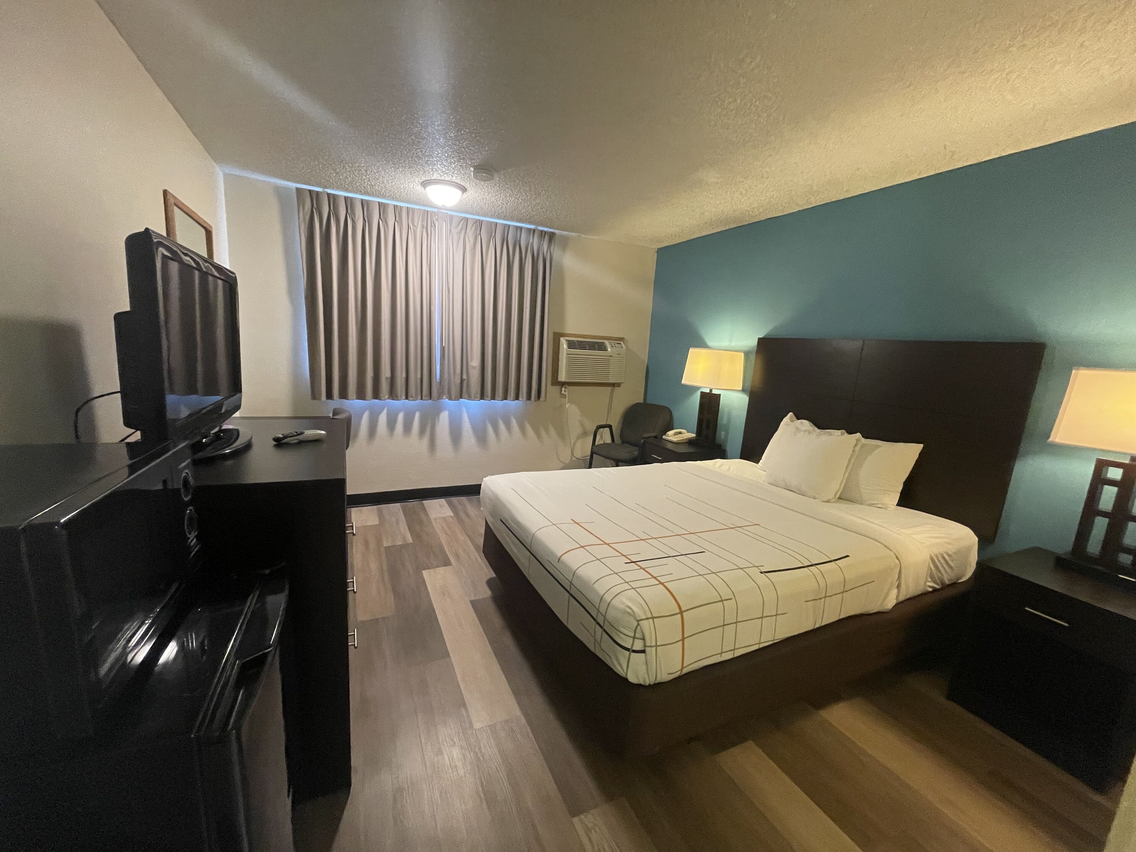 Una habitación de hotel con cama, escritorio y televisión.
