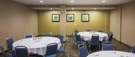 Une salle de conférence avec des tables rondes, des chaises et des tableaux encadrés accrochés au mur.