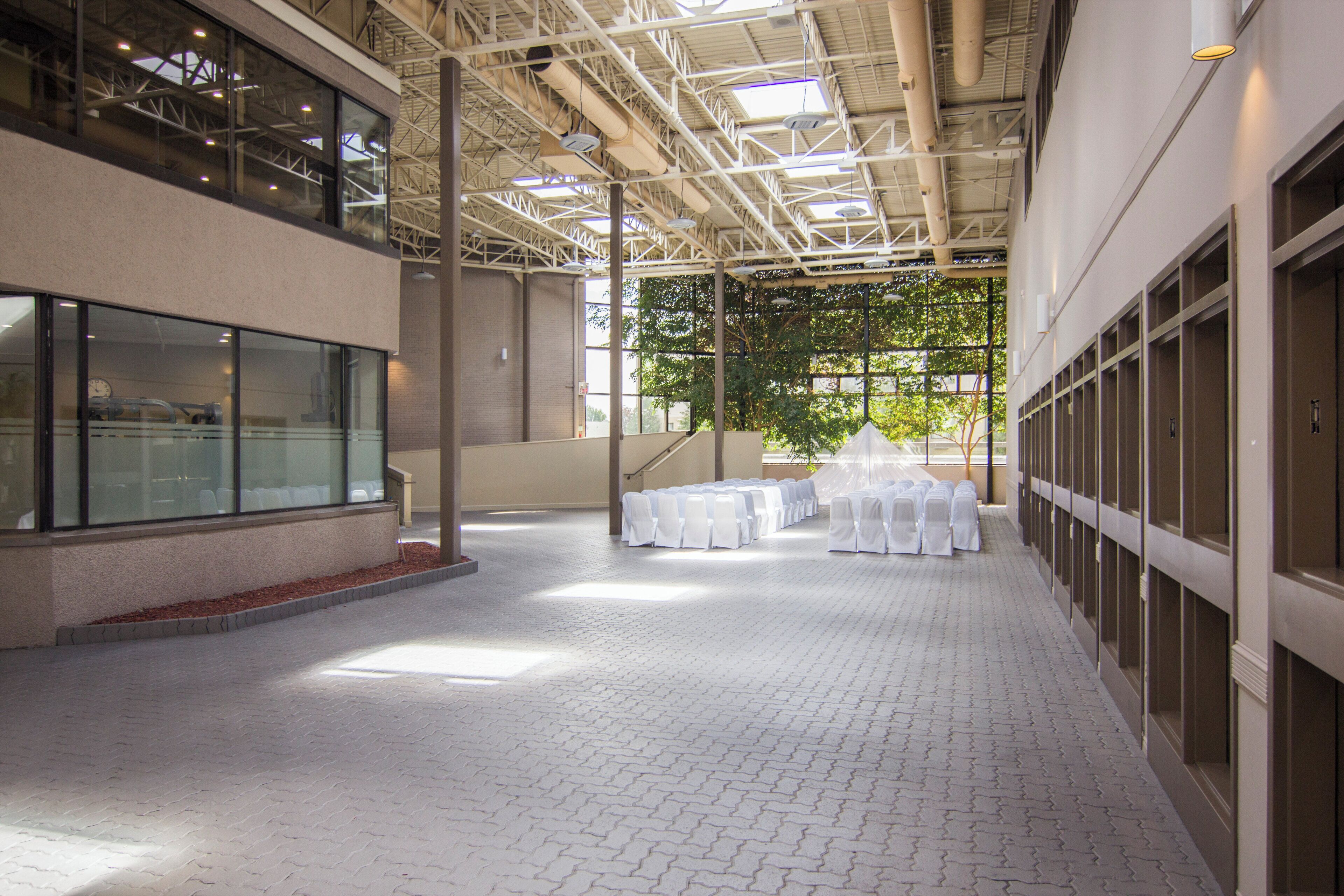An indoor space with a high ceiling, large windows, and a tiled floor.
