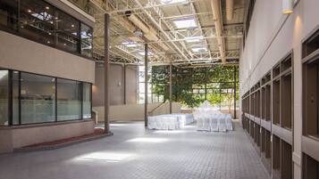 An indoor space with a high ceiling, large windows, and a tiled floor.