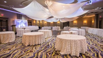 Un salón de banquetes con mesas redondas cubiertas con manteles blancos, dispuestas en filas.