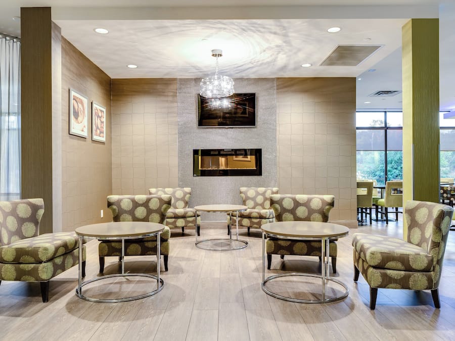 A lobby with a fireplace, seating area, and large windows.