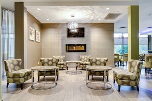 A lobby with a fireplace, seating area, and large windows. - Holiday Inn Sudbury by IHG (Sudbury)