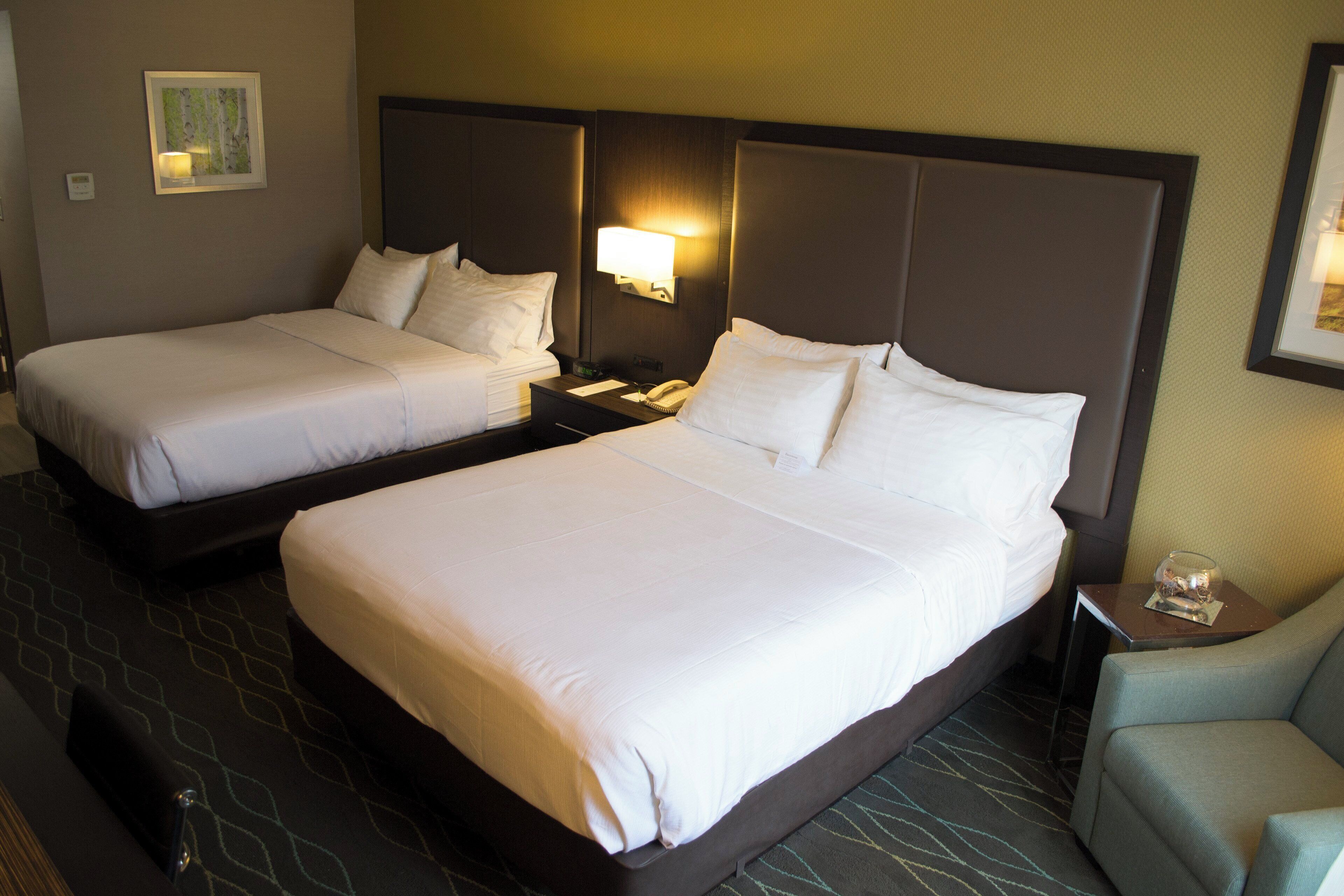 Una habitación de hotel con dos camas, una mesita de noche, una lámpara y una silla.