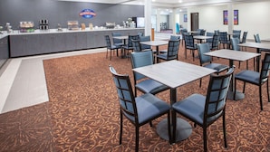 A breakfast area with a counter, seating, and a carpeted floor. - Baymont Inn & Suites Grand Rapids Near Downtown (Grand Rapids)