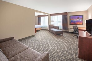 A hotel room with a bed, a sofa, a desk, and a TV. - Baymont Inn & Suites Grand Rapids Near Downtown (Grand Rapids)