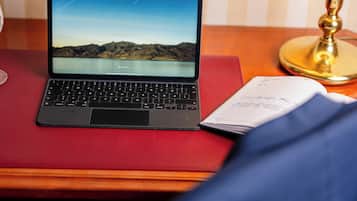 Una computadora portátil sobre una mesa roja, con un cuaderno a su lado.