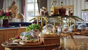 Monipuolinen buffetpöytä, jossa on tarjolla erilaisia ruokia sekä koristeellinen teekuppisetti.
