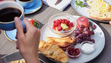 Ein Frühstückstisch mit Croissants, Obst und Kaffee.