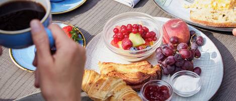 A breakfast setting with croissants, fruit, and coffee on a table.