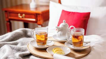 Un desayuno ordenado con dos tazas de té, una tetera, rodajas de limón y un recipiente con frutos secos sobre una bandeja.