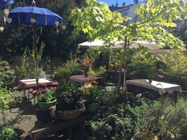Un jardín al aire libre con macetas, mesas y sombrillas.