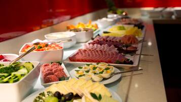 En buffet med et udvalg af madvarer, herunder kød, oste og grøntsager.