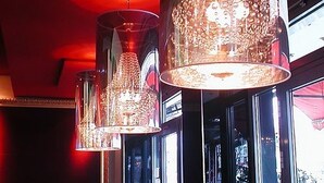 Multiple hanging chandeliers with a reflective surface, suspended from the ceiling in a room with large windows. - Cityhotel Monopol (Hamburg)