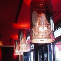 Mehrere hängende Kronleuchter mit reflektierender Oberfläche, die von der Decke in einem Raum mit großen Fenstern hängen.