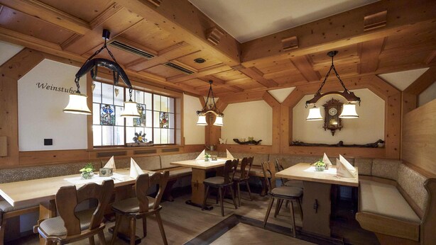 Een gezellig restaurant met houten balken, een lange gemeenschappelijke tafel en een klok aan de muur.