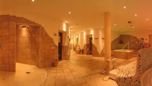Een wellnessruimte met een jacuzzi, zitplaatsen en een muurschildering.