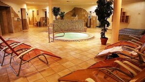 Een hotellobby met een centraal gelegen whirlpool, een zithoek en potplanten.