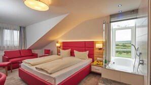 Een moderne slaapkamer met een rood bed, een groot raam, een badkuip en een rode bank.