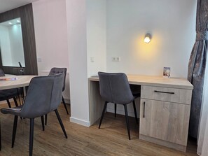 A modern room with a wooden desk, two chairs, a mirror, and a wall-mounted light. - Flair Hotel Landgasthof Roger (Loewenstein)