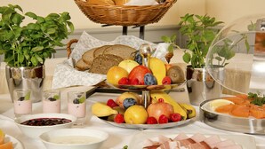 A buffet table with various food items, including bread, fruits, and meats. - Hotel Schwarzer Bär (Jena)