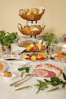 Una mesa de buffet con diversos alimentos, como pan, frutas y carnes.
