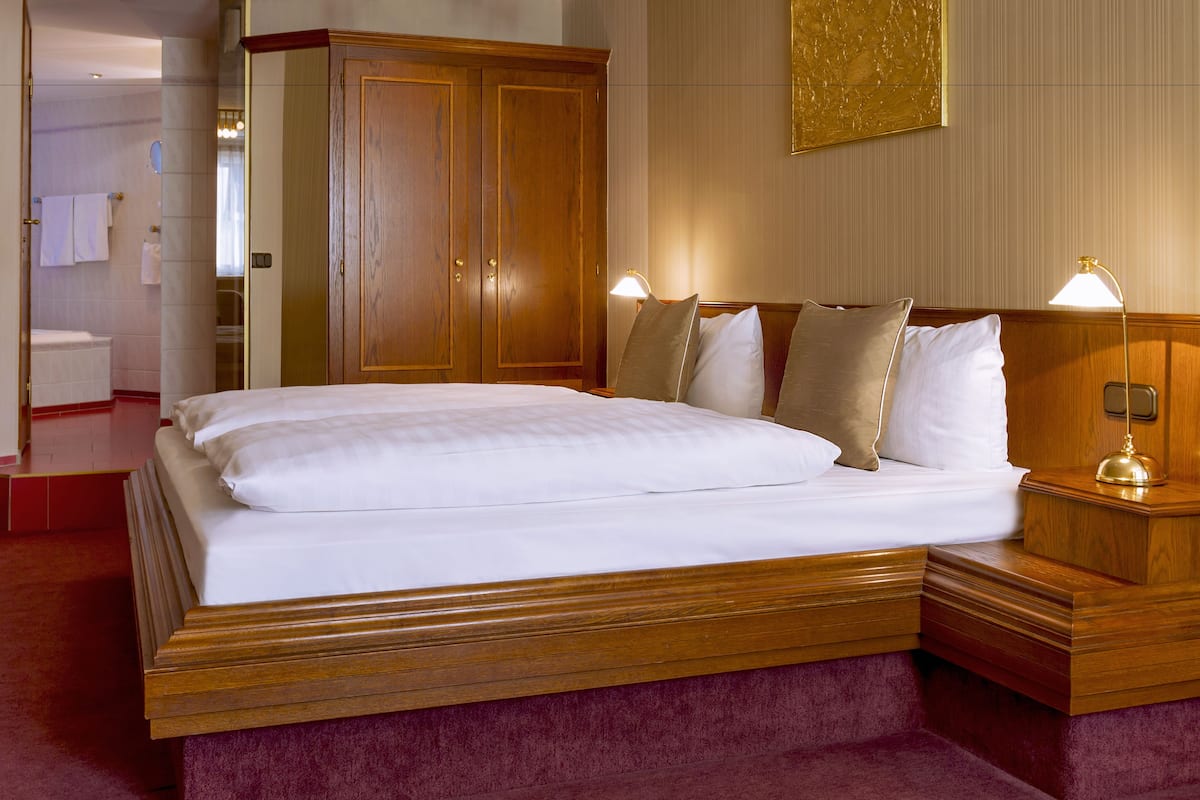 Ein Hotelzimmer mit einem großen Bett, einem Holzkopfteil und Nachttischlampen.