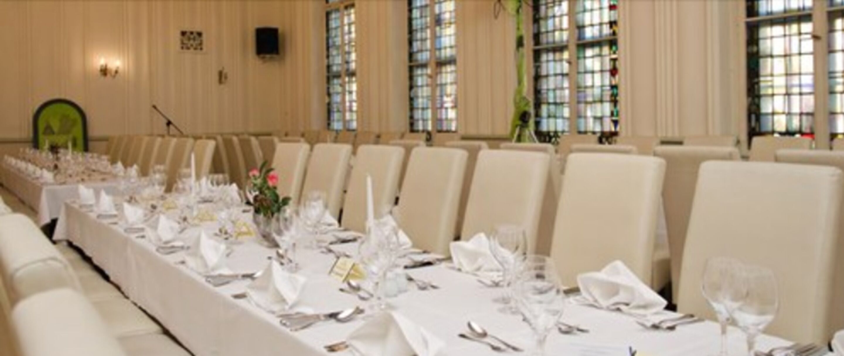 A conference room with a long table set for a formal event, surrounded by chairs.