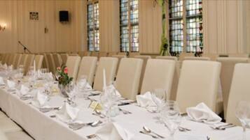 A conference room with a long table set for a formal event, surrounded by chairs.