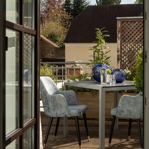 An outdoor patio with a table and two chairs, a wooden fence, and a garden area.