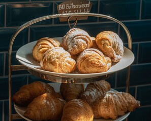 A display of assorted pastries, including croissants and other baked goods, arranged on a tiered stand.