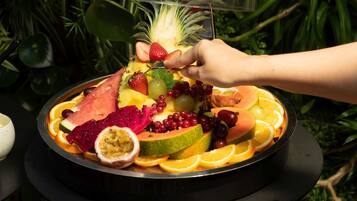 A fruit platter with a variety of fruits including strawberries, grapes, and dragon fruit, arranged on a black tray.