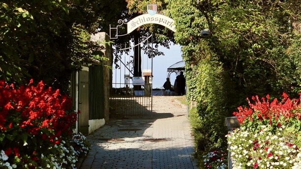 Un chemin menant à l’entrée d’un parc, avec un panneau indiquant « Schlosspark ».