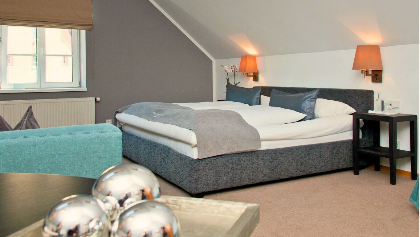 Un dormitorio moderno con cama, lámparas de noche, mesitas auxiliares y vistas al exterior.