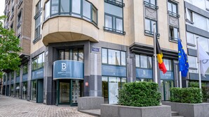A modern building with a curved corner entrance, a sign for 'B Apart Hotels', and flags of Belgium and the European Union. - B-aparthotel Ambiorix (Brussels)