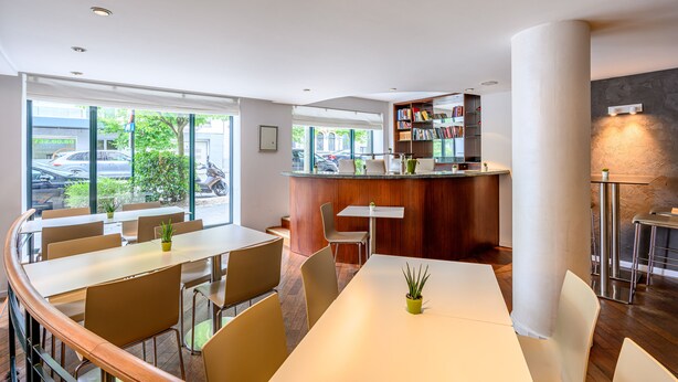 A modern hotel lobby with a bar area, seating arrangements, and a view of the street. - B-aparthotel Ambiorix (Brussels)